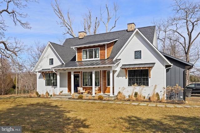 view of front of property with a porch, metal roof, roof with shingles, a standing seam roof, and a front lawn