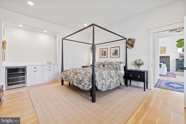 bedroom featuring beverage cooler, a dry bar, recessed lighting, and light wood-style floors