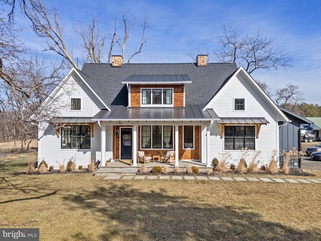 modern farmhouse featuring covered porch, metal roof, a standing seam roof, and a front yard