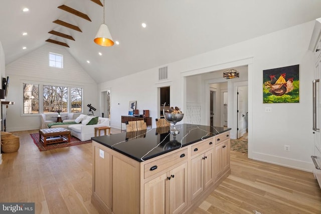 kitchen featuring high vaulted ceiling, dark countertops, open floor plan, and light wood finished floors