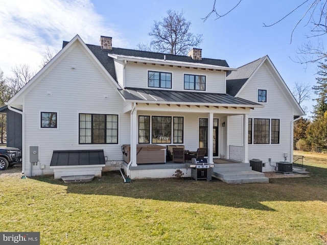 back of property featuring covered porch, metal roof, a lawn, and a standing seam roof