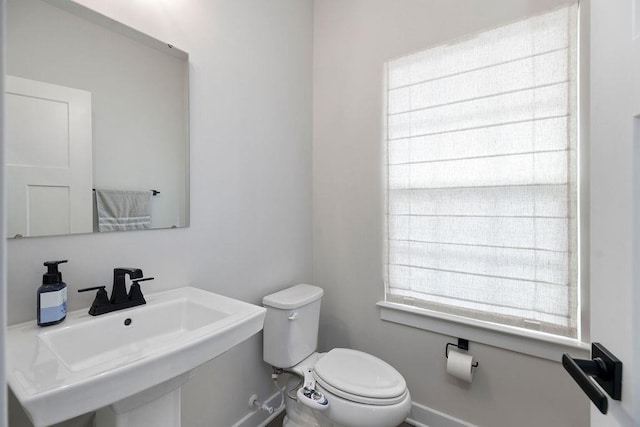 bathroom featuring baseboards, a sink, and toilet