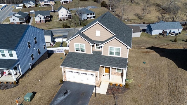 view of front facade featuring a garage, a residential view, and aphalt driveway