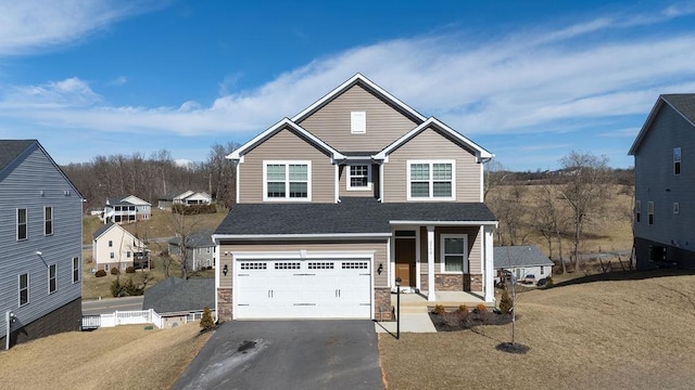 traditional-style home featuring a shingled roof, stone siding, aphalt driveway, an attached garage, and a porch