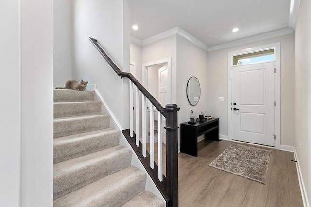 foyer featuring crown molding, wood finished floors, and baseboards