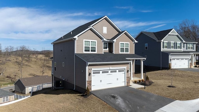 traditional-style house with a garage, stone siding, and aphalt driveway