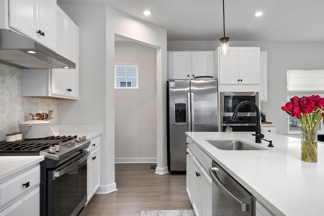 kitchen featuring under cabinet range hood, stainless steel appliances, a sink, white cabinetry, and backsplash