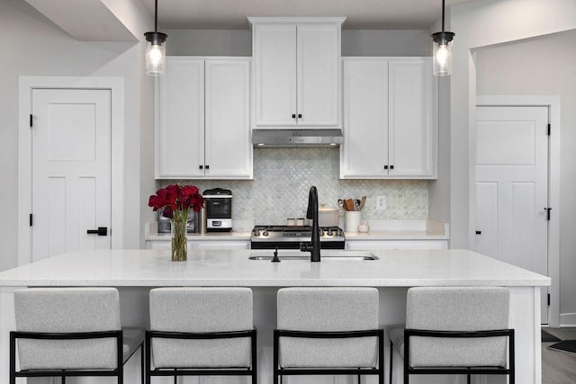 kitchen featuring white cabinets, backsplash, decorative light fixtures, and under cabinet range hood