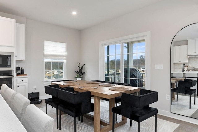 dining space featuring baseboards, wood finished floors, and recessed lighting