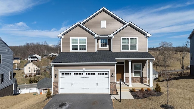 traditional-style house featuring stone siding, aphalt driveway, roof with shingles, an attached garage, and a porch