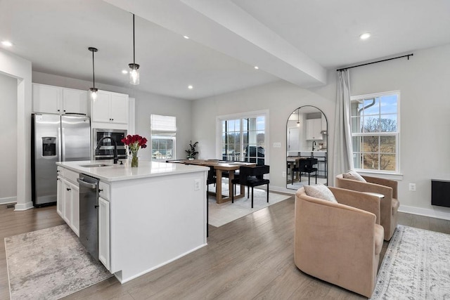 kitchen with light wood-style floors, a sink, a wealth of natural light, and stainless steel fridge with ice dispenser