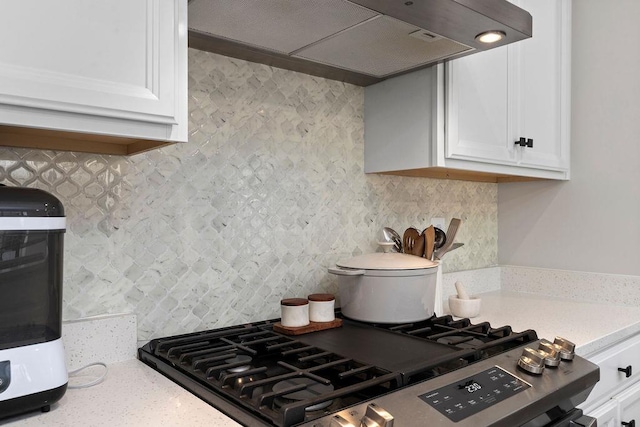 kitchen featuring backsplash, white cabinets, under cabinet range hood, and stainless steel gas range oven