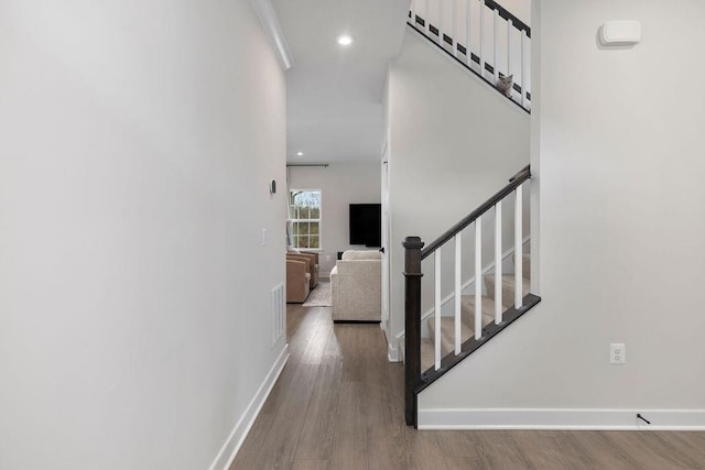 hallway featuring recessed lighting, wood finished floors, visible vents, baseboards, and stairs