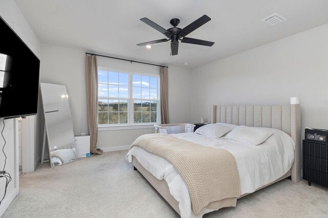 bedroom with light carpet, ceiling fan, visible vents, and baseboards