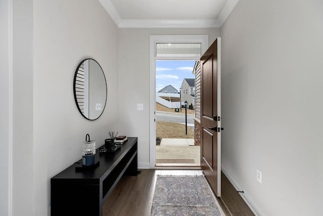 doorway with crown molding, baseboards, and wood finished floors