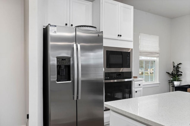 kitchen featuring appliances with stainless steel finishes, white cabinets, and light stone counters