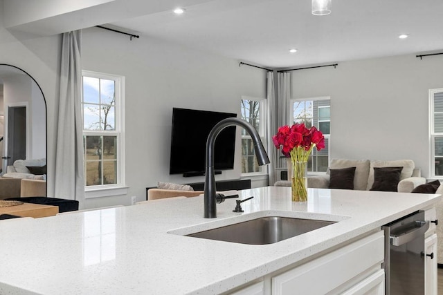 kitchen featuring open floor plan, a sink, and light stone countertops