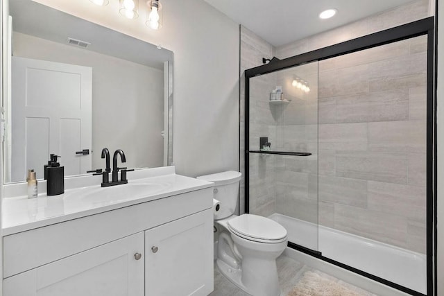 bathroom with toilet, a stall shower, visible vents, and vanity