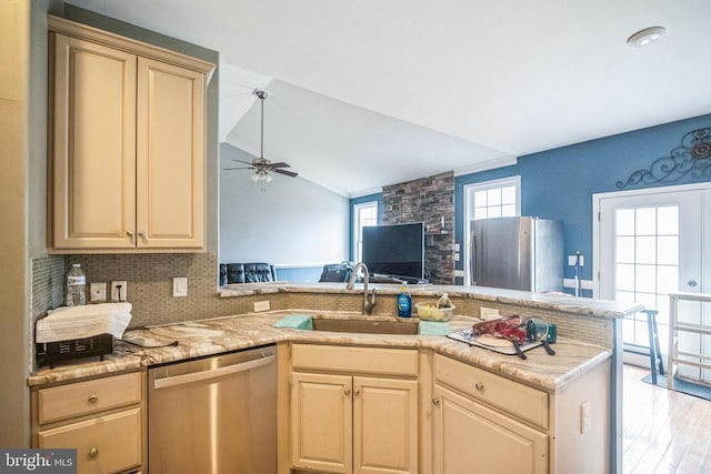 kitchen with lofted ceiling, decorative backsplash, appliances with stainless steel finishes, a sink, and ceiling fan