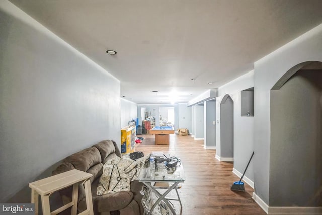 living room featuring arched walkways, wood finished floors, and baseboards