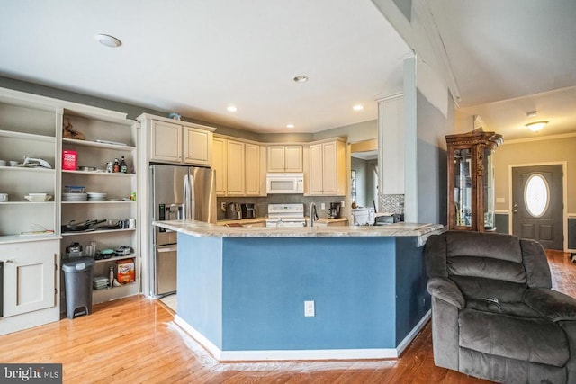 kitchen featuring cream cabinets, a peninsula, white appliances, light wood finished floors, and tasteful backsplash