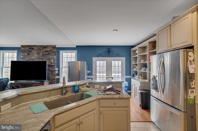 kitchen with stainless steel fridge, cream cabinetry, a sink, and french doors