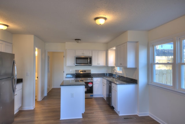 kitchen with sink, dark wood-type flooring, white cabinetry, stainless steel appliances, and a textured ceiling