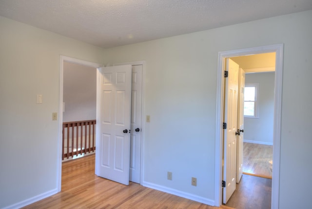 unfurnished bedroom with a closet, a textured ceiling, and light hardwood / wood-style flooring