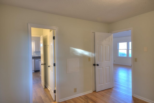 hallway with a textured ceiling and light wood-type flooring