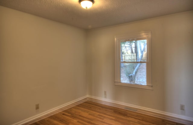 unfurnished room featuring hardwood / wood-style flooring and a textured ceiling