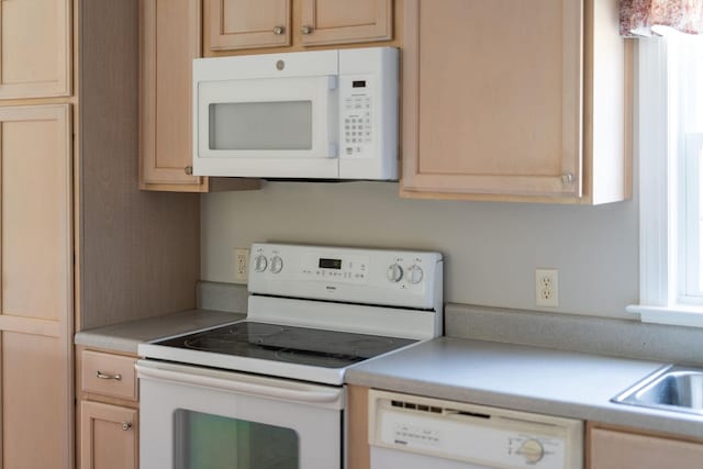 kitchen featuring sink, light brown cabinetry, and white appliances