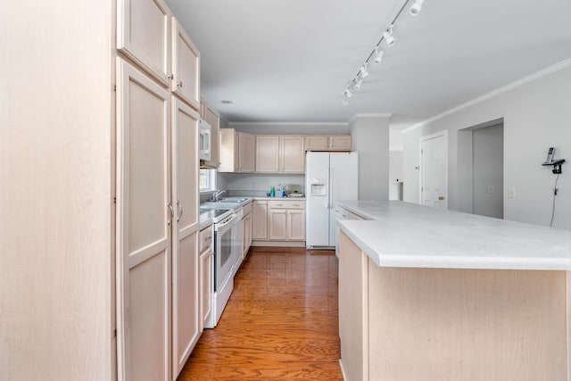 kitchen with sink, crown molding, white appliances, hardwood / wood-style flooring, and kitchen peninsula