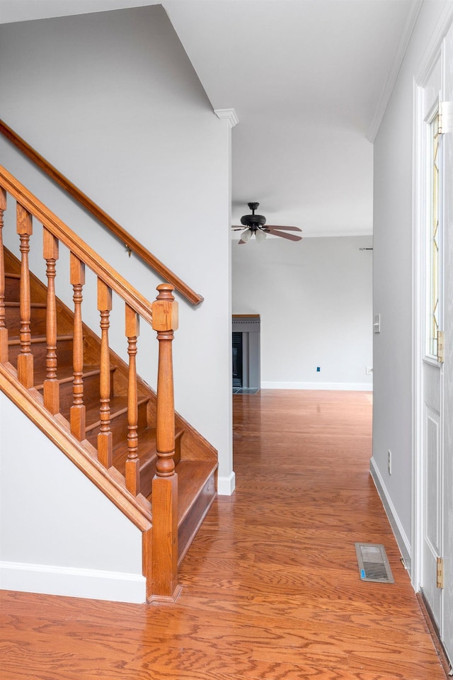 stairway featuring hardwood / wood-style flooring, ceiling fan, and crown molding