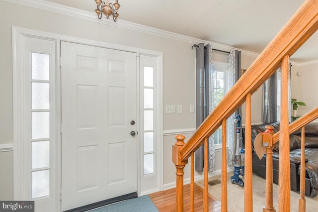 entrance foyer with hardwood / wood-style flooring, ornamental molding, and a chandelier