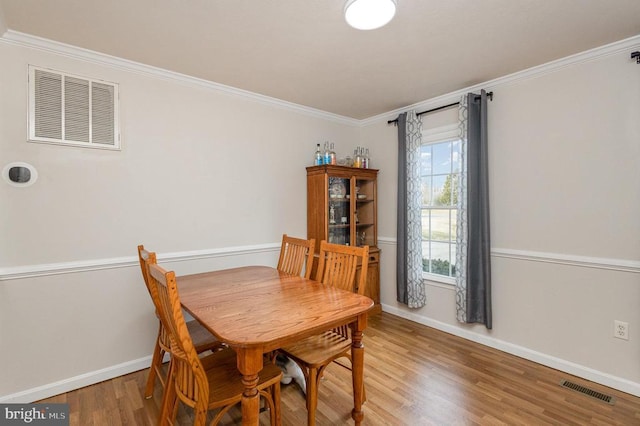 dining space with hardwood / wood-style flooring and ornamental molding