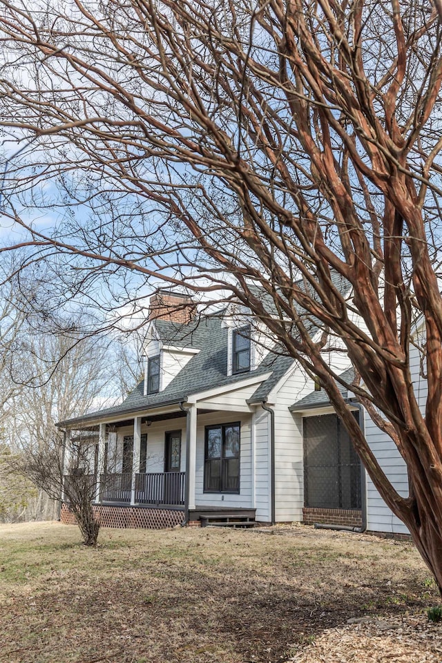 view of front facade featuring a porch, a front lawn, and a shingled roof