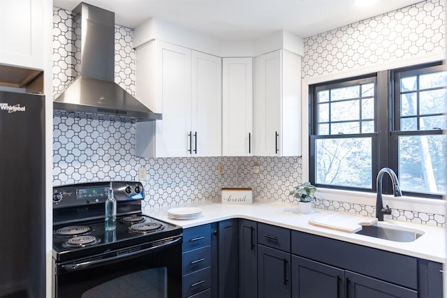 kitchen featuring light countertops, white cabinets, a sink, black appliances, and wall chimney exhaust hood