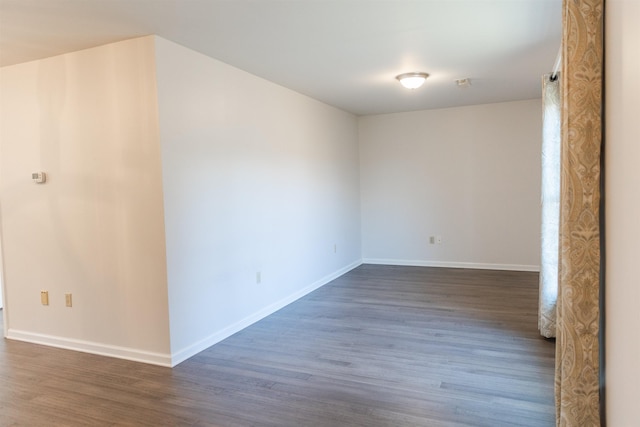 unfurnished room featuring baseboards and dark wood finished floors