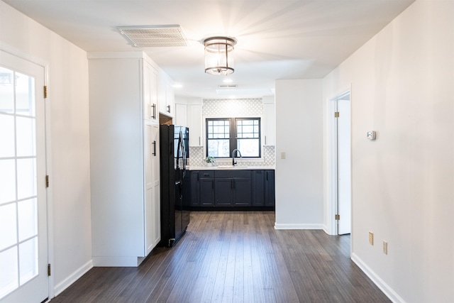 kitchen with light countertops, visible vents, freestanding refrigerator, white cabinets, and a sink