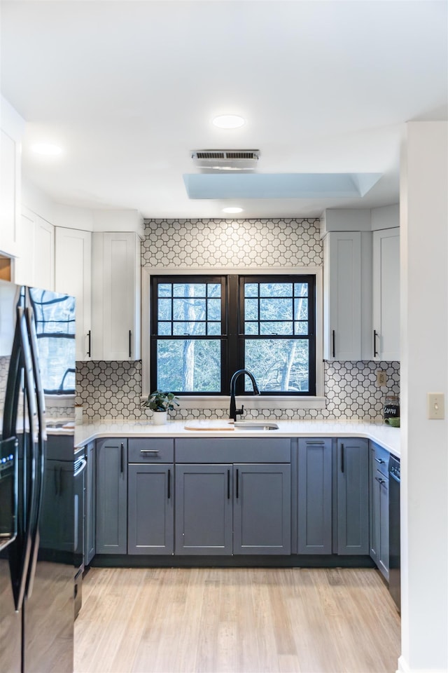 kitchen with gray cabinets, light countertops, a sink, and black appliances