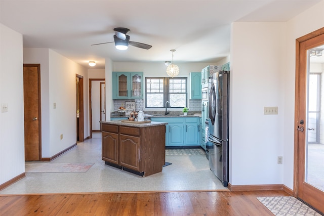 kitchen featuring a center island, decorative light fixtures, backsplash, glass insert cabinets, and freestanding refrigerator