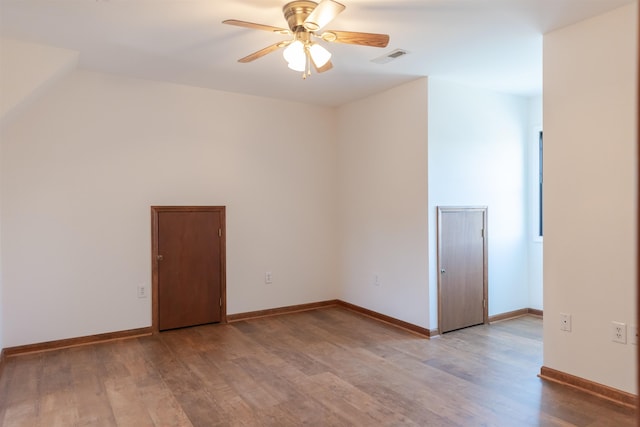 empty room with light wood-type flooring, visible vents, ceiling fan, and baseboards