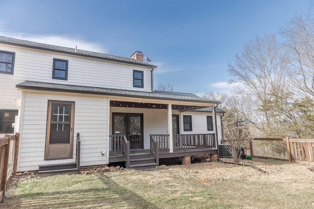 rear view of house featuring central air condition unit, a yard, a chimney, and fence