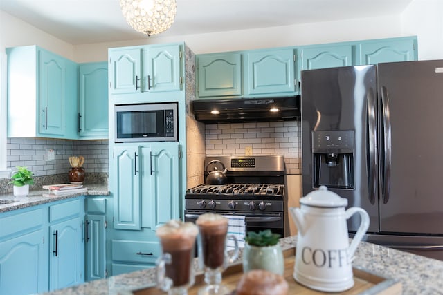 kitchen with light stone counters, under cabinet range hood, stainless steel appliances, blue cabinetry, and backsplash