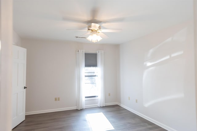 spare room featuring dark wood finished floors, a ceiling fan, and baseboards