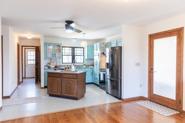 kitchen with stainless steel appliances, a kitchen island, light wood-style floors, tasteful backsplash, and pendant lighting