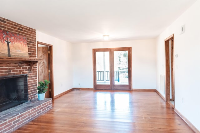 unfurnished living room with french doors, a fireplace, visible vents, light wood-style flooring, and baseboards