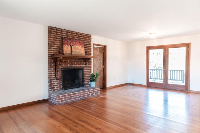 unfurnished living room with french doors, a fireplace, wood finished floors, and baseboards