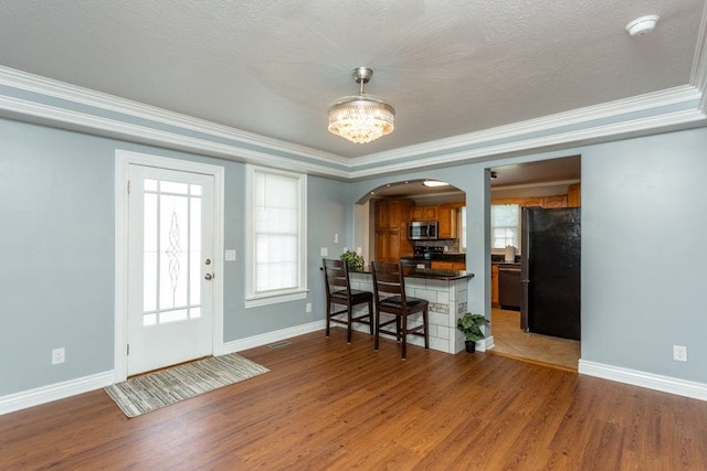 interior space with hardwood / wood-style flooring, ornamental molding, an inviting chandelier, and a textured ceiling