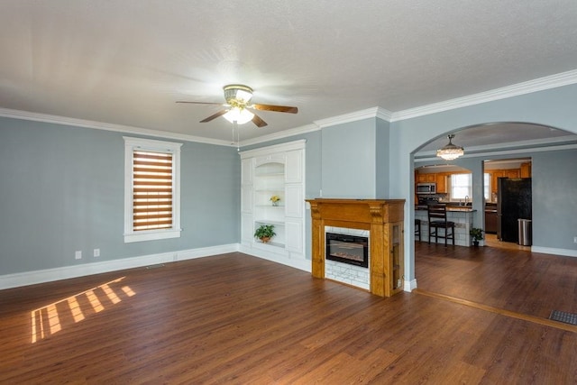 unfurnished living room with crown molding, dark wood-type flooring, built in features, and ceiling fan